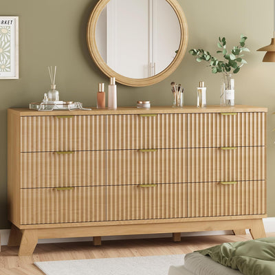 Fluted natural oak 9-drawer dresser with wave-textured drawer fronts and metal pulls, styled in a bedroom with a round mirror above