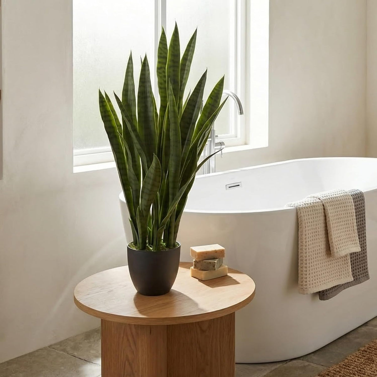 Artificial snake plant with black planter, styled in a living room corner