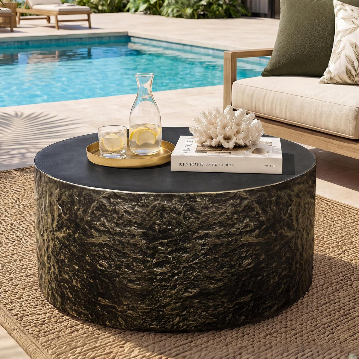Round travertine-look outdoor coffee table, off-white, styled on a patio with seating