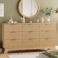 Fluted natural oak 9-drawer dresser with wave-textured drawer fronts and metal pulls, styled in a bedroom with a round mirror above
